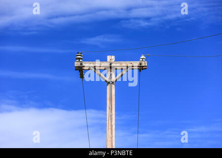 Immagine concettuale di un palo telefonico e i fili contro un cielo blu. Foto Stock