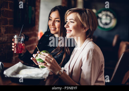 Due amiche avente cena con sandwich di verde in burger bar. Foto Stock