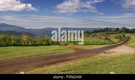 Un solitario strada si snoda attraverso la campagna sull'altopiano di Atherton vicino a Cairns in Tropical North Queensland Australia Foto Stock