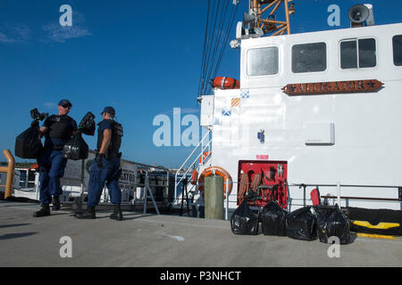 Coast Guard funzionari di polizia a bordo del guardacoste offload del coccodrillo di circa 150 chilogrammi di cocaina del valore di 5 milioni di dollari stimati valore all'ingrosso a Coast Guard Settore San Pietroburgo, Florida, Lunedì 18 Luglio, 2016. Il Coccodrillo equipaggio trasferito anche quattro sospetti trafficanti alle autorità degli Stati Uniti per il perseguimento dall'Assistente U.S. Ufficio del procuratore per il distretto centrale della Florida. (U.S. Coast Guard foto di Sottufficiali di seconda classe Ashley J. Johnson) Foto Stock