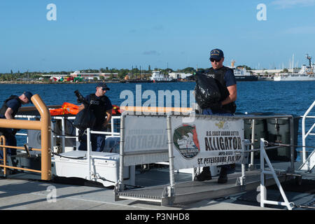Funzionari di polizia a bordo del guardacoste offload del coccodrillo di circa 150 chilogrammi di cocaina del valore di 5 milioni di dollari stimati valore all'ingrosso a Coast Guard Settore San Pietroburgo, Florida, Lunedì 18 Luglio, 2016. Una guardia costiera di applicazione della legge del team di distacco a bordo della USS Shamal, U.S. Navy 179-piede Patrol navi costiere basato a Mayport, Florida, e l'equipaggio Shamal sequestrati di cocaina durante due distinti interdictions nel Mar dei Caraibi. (U.S. Coast Guard foto di Sottufficiali di seconda classe Ashley J. Johnson) Foto Stock