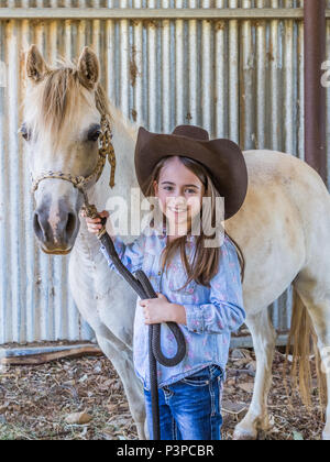 Australiano giovane ragazza che indossa un stetson, tenendo sul suo pony in una stalla. Foto Stock