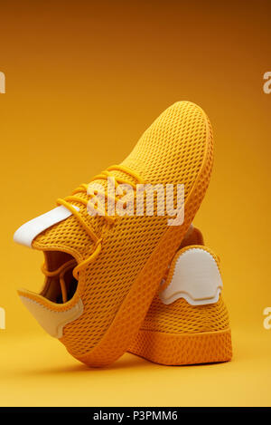 Coppia di giallo sport scarpe su sfondo arancione Foto Stock