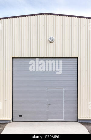 Magazzini industriali esterno. chiuso di metallo grigio gate con porta Foto Stock