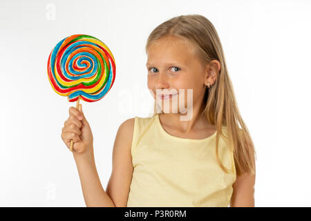 Carino bambino contento con la caramella lecca-lecca, felice ragazza mangiare zucchero grande lecca-lecca, kid mangiare dolci. bambino sorpreso con la caramella. isolato su sfondo bianco, Foto Stock