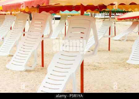 Ripiegate sdraio e ombrelloni sulla spiaggia sabbiosa. Foto Stock