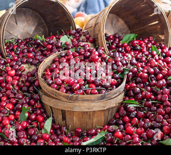 Yummy cherry bacche impilati su un tavolo decorato con un cesto su un mercato degli agricoltori Foto Stock