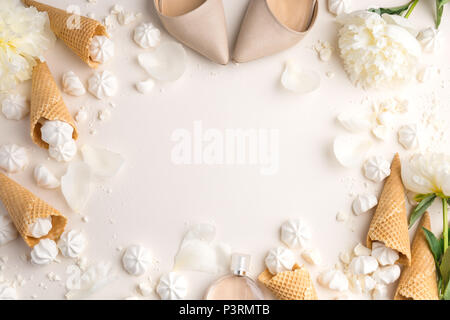 Primavera Estate gara femminile dello sfondo. Vista da sopra con peonia, scarpe, gelato coni di cialda e merengue in beige. Vista da sopra con lo spazio di copia Foto Stock