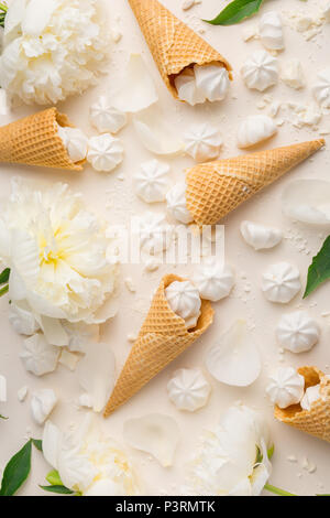 Primavera Estate sfondo di gara. Vista da sopra con peonia, ciliegie, gelato coni di cialda e merengue in beige. Vista da sopra con lo spazio di copia Foto Stock