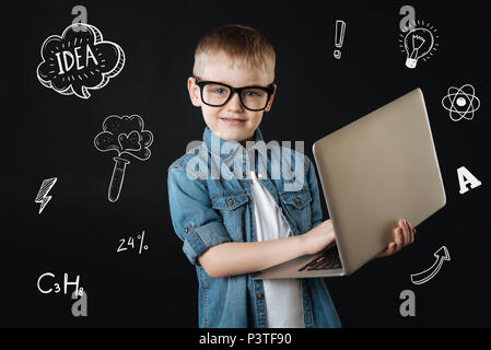 Bambino progressiva fiduciosi tenendo un laptop moderno Foto Stock