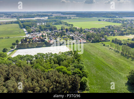 Vista aerea di un piccolo villaggio nella distanza dietro un pezzo di foresta e un campo di asparagi coperto con un foglio di alluminio, fatta con drone Foto Stock