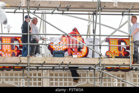 Brighton Regno Unito 19 Giugno 2018 - operai regolando la lettera P come la nuova insegna al neon per Brighton Palace Pier è eretto . Il molo è stato costruito nel 1890 e chiamato Brighton Palazzo Marino e il molo ma divenne noto localmente come il Palace Pier fino al 2000 quando è stato cambiato il nome di Brighton Pier. Luke Johnson presidente esecutivo del Molo di Brighton gruppo adesso ha annunciato che sarà noto come il Brighton Palace Pier Credit: Simon Dack/Alamy Live News Foto Stock