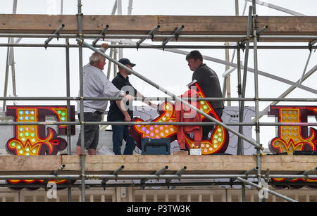 Brighton Regno Unito 19 Giugno 2018 - operai regolando la lettera P come la nuova insegna al neon per Brighton Palace Pier è eretto . Il molo è stato costruito nel 1890 e chiamato Brighton Palazzo Marino e il molo ma divenne noto localmente come il Palace Pier fino al 2000 quando è stato cambiato il nome di Brighton Pier. Luke Johnson presidente esecutivo del Molo di Brighton gruppo adesso ha annunciato che sarà noto come il Brighton Palace Pier Credit: Simon Dack/Alamy Live News Foto Stock