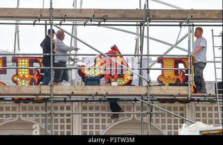 Brighton Regno Unito 19 Giugno 2018 - operai regolando la lettera P come la nuova insegna al neon per Brighton Palace Pier è eretto . Il molo è stato costruito nel 1890 e chiamato Brighton Palazzo Marino e il molo ma divenne noto localmente come il Palace Pier fino al 2000 quando è stato cambiato il nome di Brighton Pier. Luke Johnson presidente esecutivo del Molo di Brighton gruppo adesso ha annunciato che sarà noto come il Brighton Palace Pier Credit: Simon Dack/Alamy Live News Foto Stock