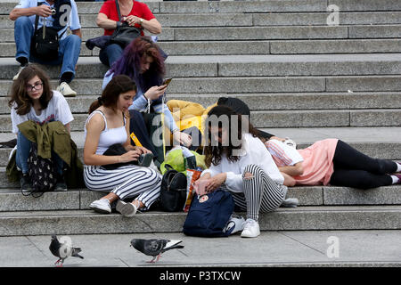 Trafalgar Square. Londra. Regno Unito 19 Giugno 2018 - turisti che si siedono sui gradini di Trafalgar Square in un caldo pomeriggio. La temperatura nella capitale che potrebbe raggiungere 25 gradi celsius e caldo è previsto. Credito: Dinendra Haria/Alamy Live News Foto Stock