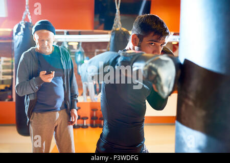 Uomo Sacco boxe con trainer su allenamento Foto Stock