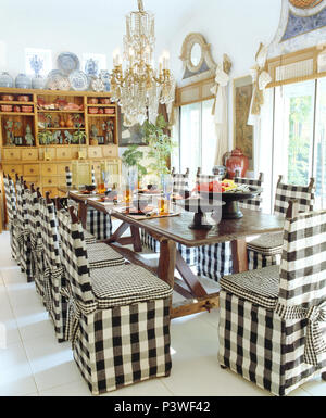 Nero+bianco a scacchi allentati i coperchi sul tavolo lungo sotto il lampadario in vetro in portoghese bianco sala da pranzo Foto Stock