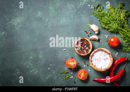Sfondo di cibo con le spezie e le erbe aromatiche e i pomodori sul tavolo di pietra. Gli ingredienti della cucina. Vista da sopra con copia spazio. Foto Stock