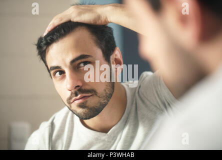 L'uomo preoccupato per Alopecia controllare i capelli per la perdita Foto Stock
