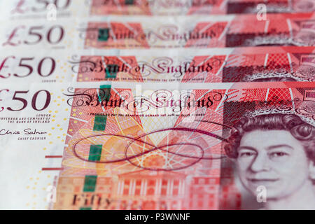 Sullo sfondo di una fila ordinata di cinquanta UK pound banconote sterling Foto Stock