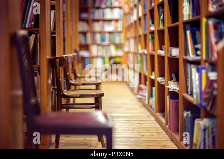 Libreria con righe di libri sugli scaffali e sedie vuote Foto Stock