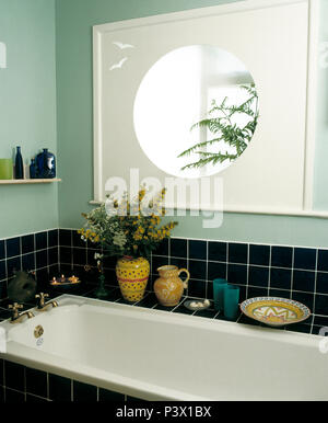 Specchio circolare sopra il bagno in verde pallido bagno con piastrelle nere splash back Foto Stock