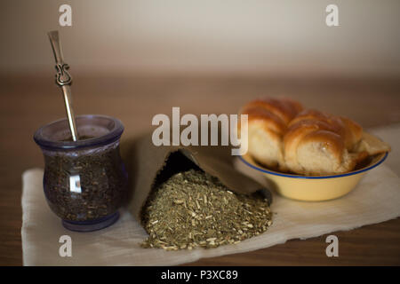 Mate argentino com saco de erva (Ilex paraguariensis) e prato Medialunas com. Foto Stock