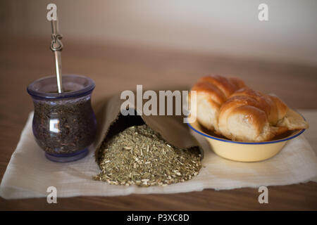 Mate argentino com saco de erva (Ilex paraguariensis) e prato Medialunas com. Foto Stock