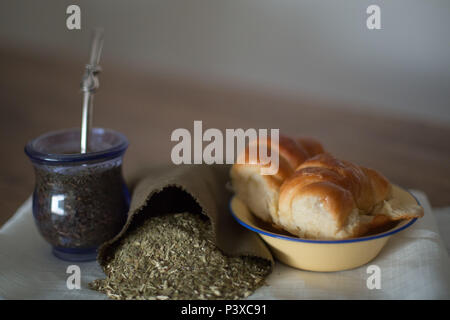 Mate argentino com saco de erva (Ilex paraguariensis) e prato Medialunas com. Foto Stock