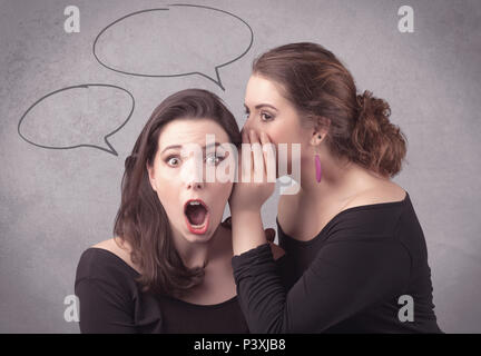 Due ragazze in chat e condividere i loro segreti concetto con tratte bolle chat sullo sfondo parete urbana. Foto Stock