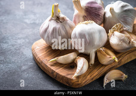 Spicchi di aglio su una pietra scura sullo sfondo. Foto Stock