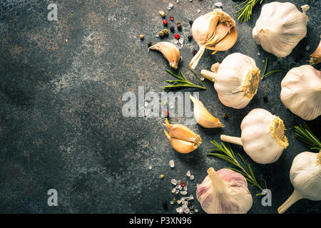 Rametti di rosmarino, pepe e aglio su una pietra scura sullo sfondo. Ingredienti per la cottura, vista dall'alto, copia dello spazio. Foto Stock