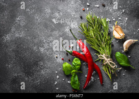 Le spezie e le erbe sul nero tavolo di pietra. Sfondo di cibo. Vista superiore, copia dello spazio. Foto Stock