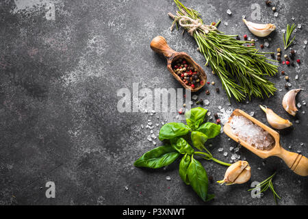 Le spezie e le erbe sul nero tavolo di pietra. Sfondo di cibo. Vista superiore, copia dello spazio. Foto Stock