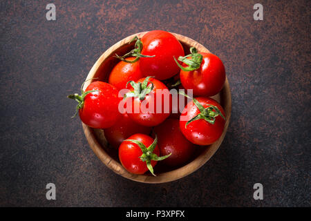 Pomodori in ciotola di legno scuro sul tavolo di pietra. Vista dall'alto. Foto Stock
