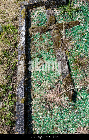 Una botte vecchia Croce che è caduto ed è giacente in erba in un cimitero. Foto Stock