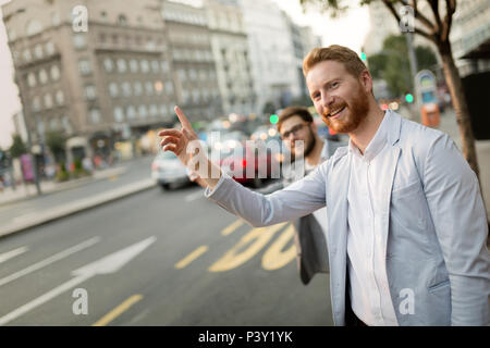 Imprenditore agitando per un taxi Foto Stock