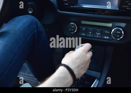 Mano che tiene la trasmissione automatica in suo automobile Foto Stock