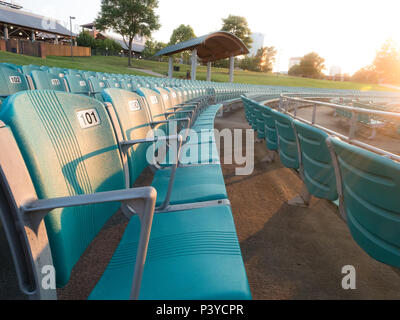 Righe di vuoto stadio verde posti in un luogo esterno al tramonto Foto Stock