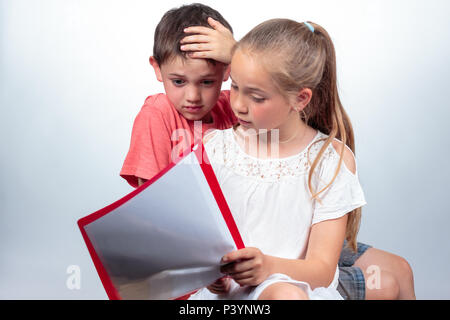 Gli scolari caucasica studiando, una ragazza carina tenendo note, spiega un ragazzo che sembra confusa e colpisce la sua mano nel suo capelli su sfondo chiaro. Foto Stock