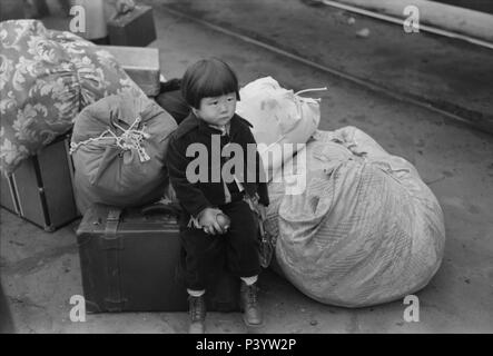 Japanese-American bambino in attesa del treno per Owens Valley durante l'evacuazione di Japanese-Americans dal West Coast zone sotto U.S. Esercito guerra ordine di emergenza, Los Angeles, California, USA, Russell Lee, Ufficio di informazione di guerra, Aprile 1942 Foto Stock