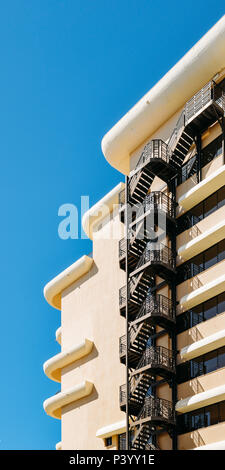 Metal fire escape sulla facciata di un edificio moderno con cielo blu Foto Stock