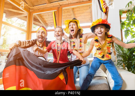 Tutta la famiglia il tifo per il calcio tedesco team nella parte anteriore della TV Foto Stock