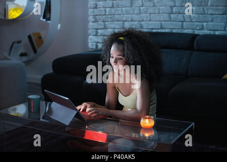 Giovane Latina donna digitando messaggio sul computer portatile di notte Foto Stock