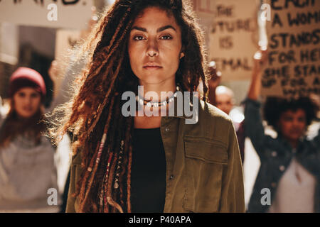 Donna in piedi all'aperto di fronte a manifestanti sulla strada. Femmina di protestare con il gruppo di attivisti all'esterno. Foto Stock