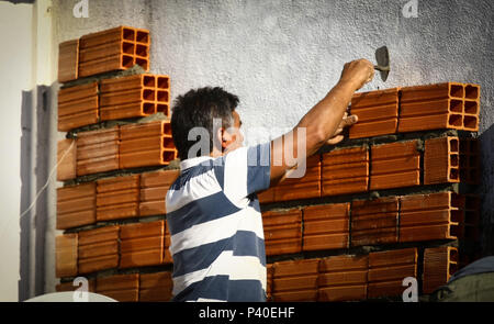 Pedreiros em construção levantando parede de tijolos. Foto Stock