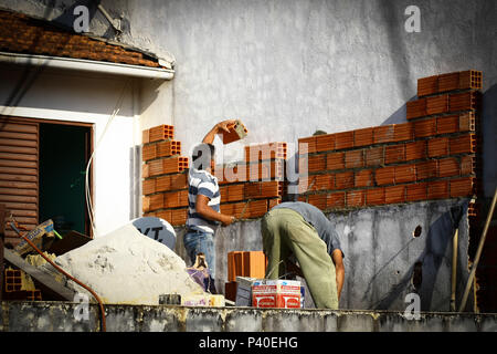 Pedreiros em construção levantando parede de tijolos. Foto Stock