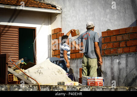 Pedreiros em construção levantando parede de tijolos. Foto Stock