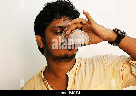 Giovane uomo di bere birra o un drink fresco dalla tazza di plastica Foto Stock
