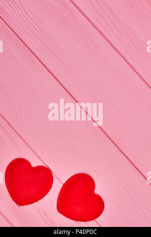 Due piccoli cuori su sfondo di legno. Feltro rosso cuori e copia dello spazio. Amore e romanticismo concetto. Foto Stock